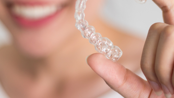 A smiling patient holds a Houston Invisalign retainer
