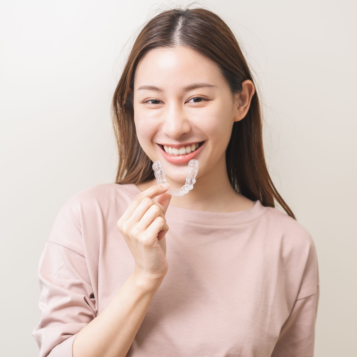 Lady with a beautiful smile holds her Houston Invisalign