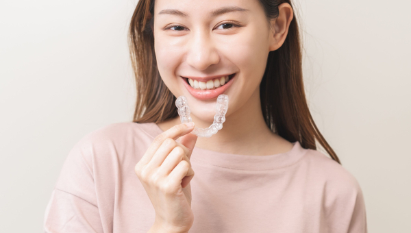Lady with a beautiful smile holds her Houston Invisalign