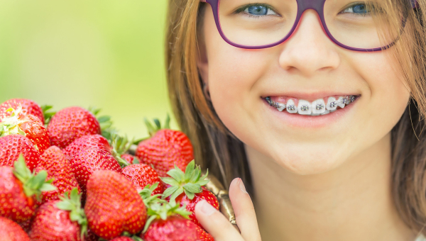 Girl holds up a basket of strawberries she can easily eat even with her South Houston dental braces.
