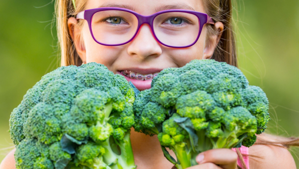 Young girl in Houston braces holds vegetables she can easily eat.