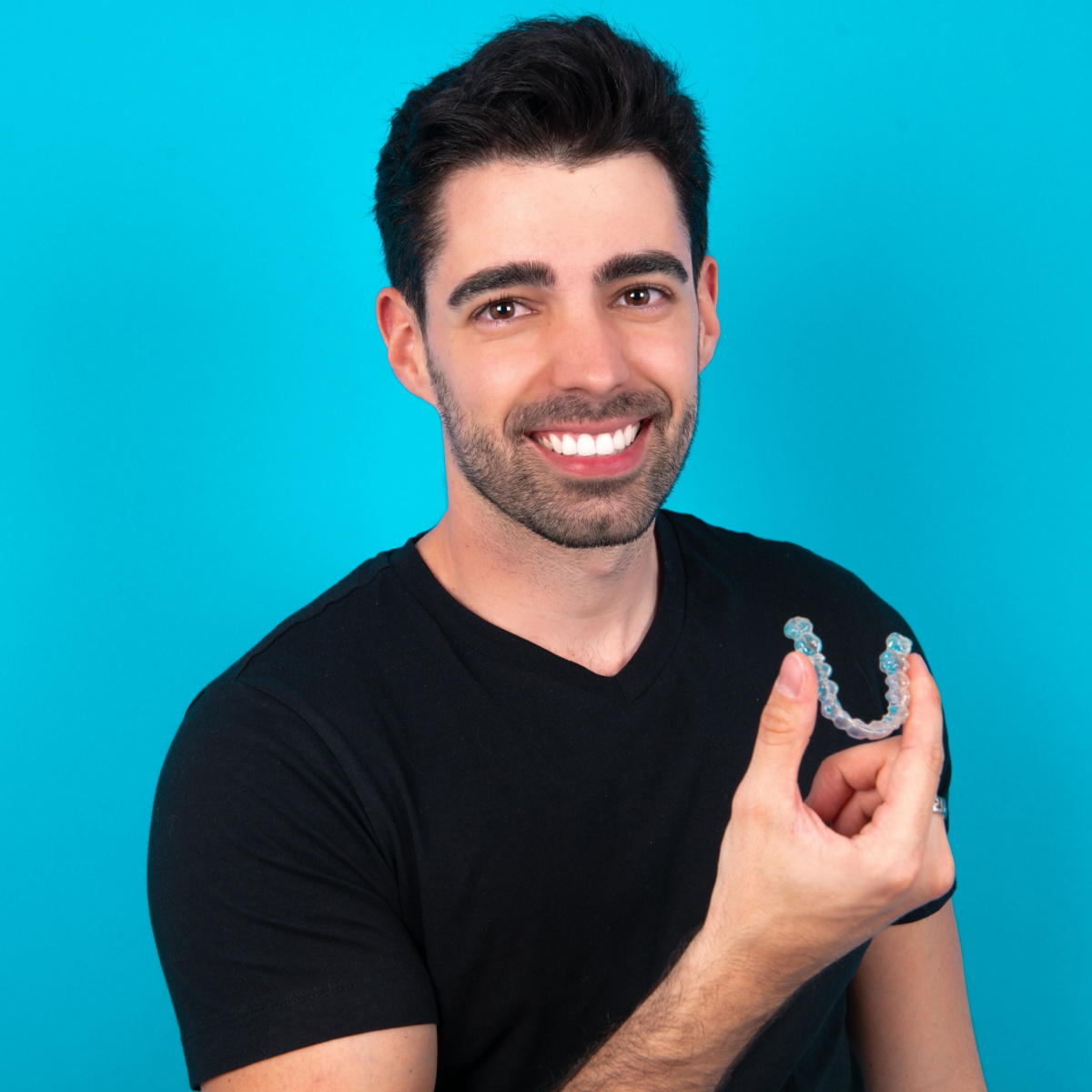 A man in black shirt smiles while holding a Houston Invisalign.