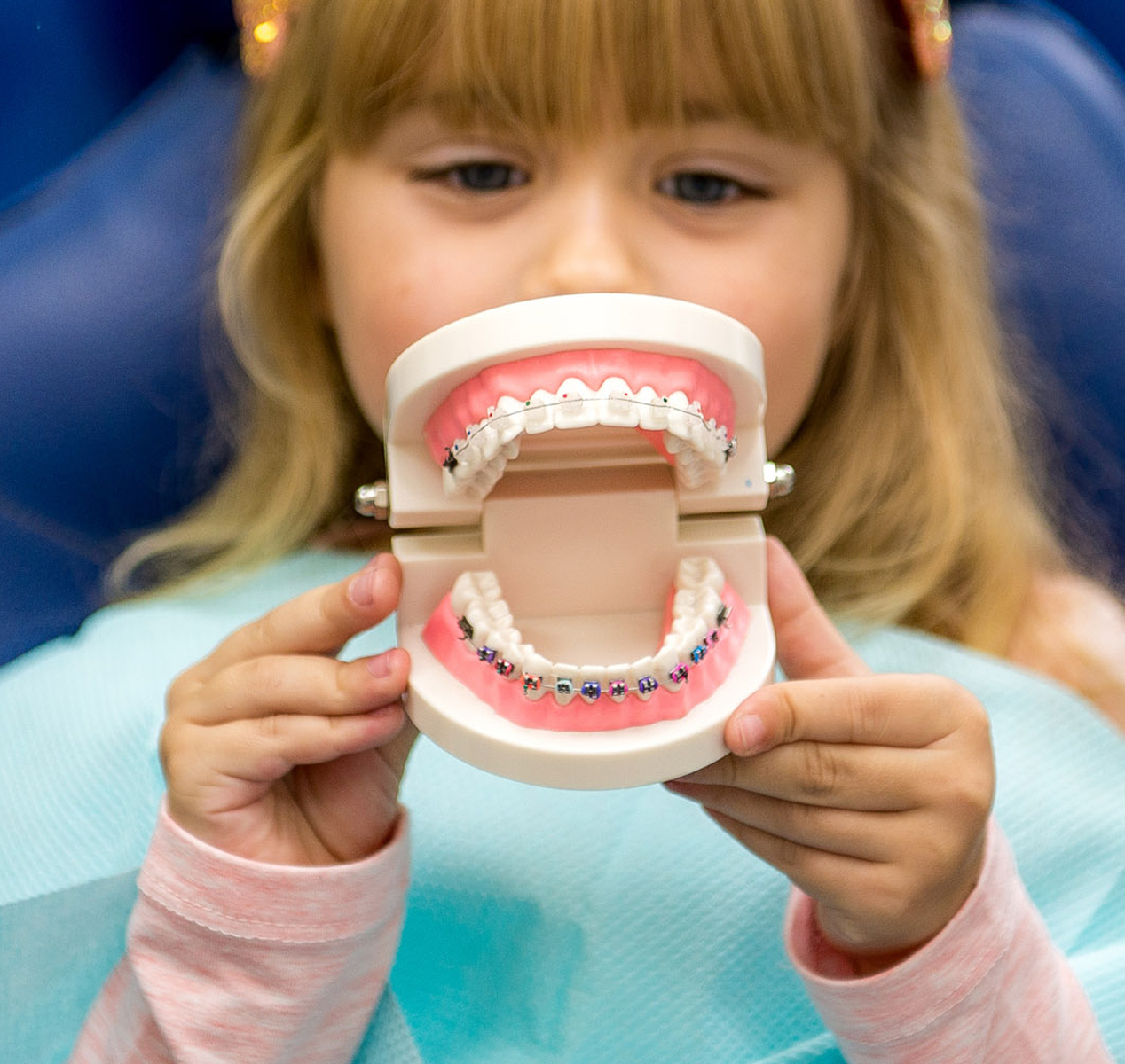 Child plays with anatomical model of teeth with braces
