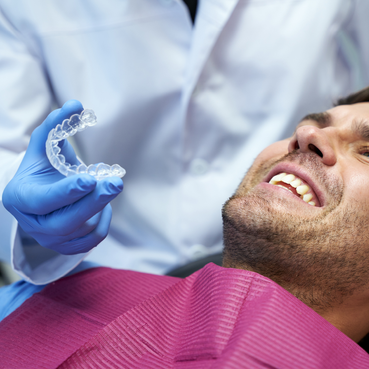 dentist holding clear aligners for patient