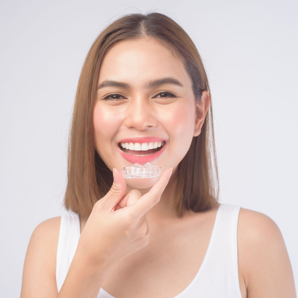 Smiling lady holding her Houston Invisalign retainers.