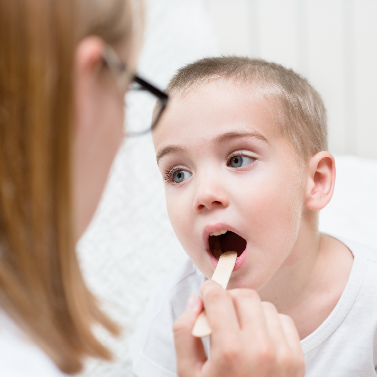 little boy having throat examined by healthcare professional
