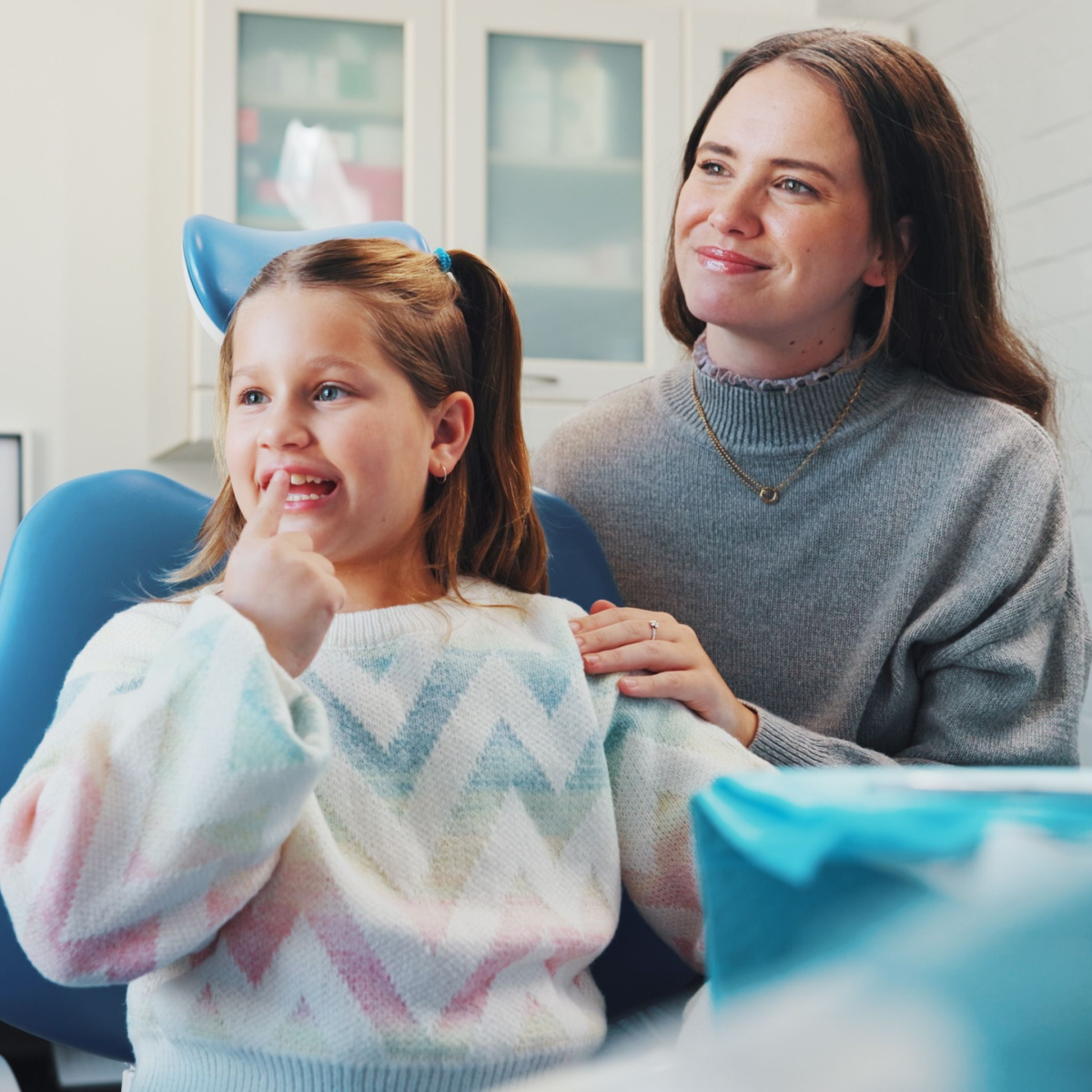 A kid accompanied by an adult smiles on her Houston dentist visit.