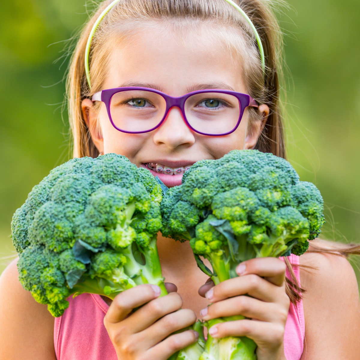 Young girl in Houston braces holds vegetables she can easily eat.